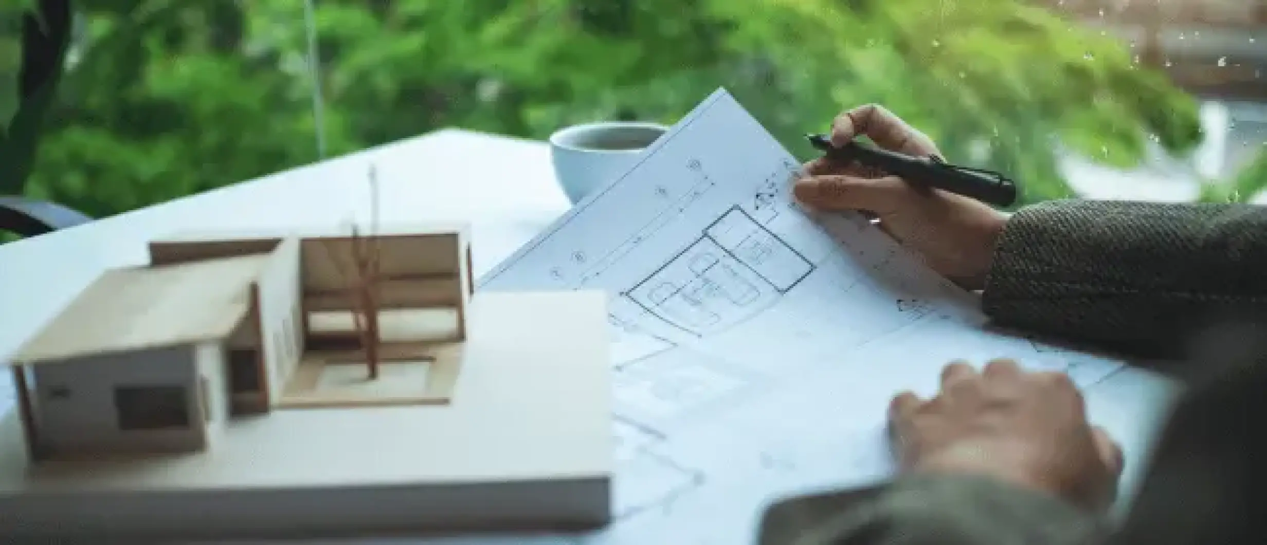 Un architecte conçoit un plan de maison personnalisée avec une maquette sur bureau