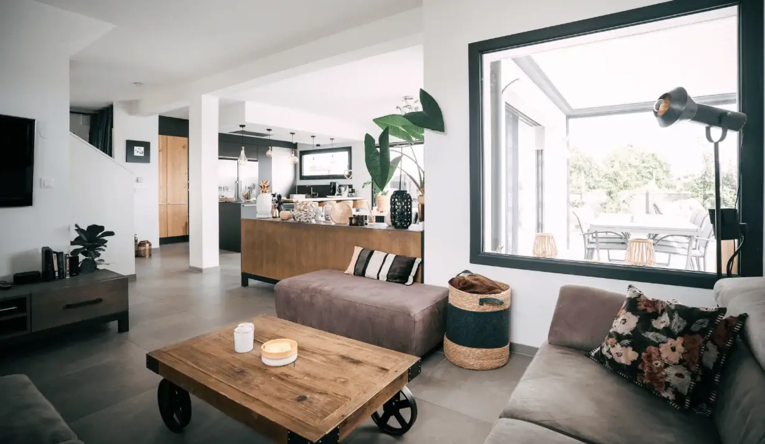 Salon contemporain ouvert sur la cuisine avec décoration bois, textile et tons neutres.