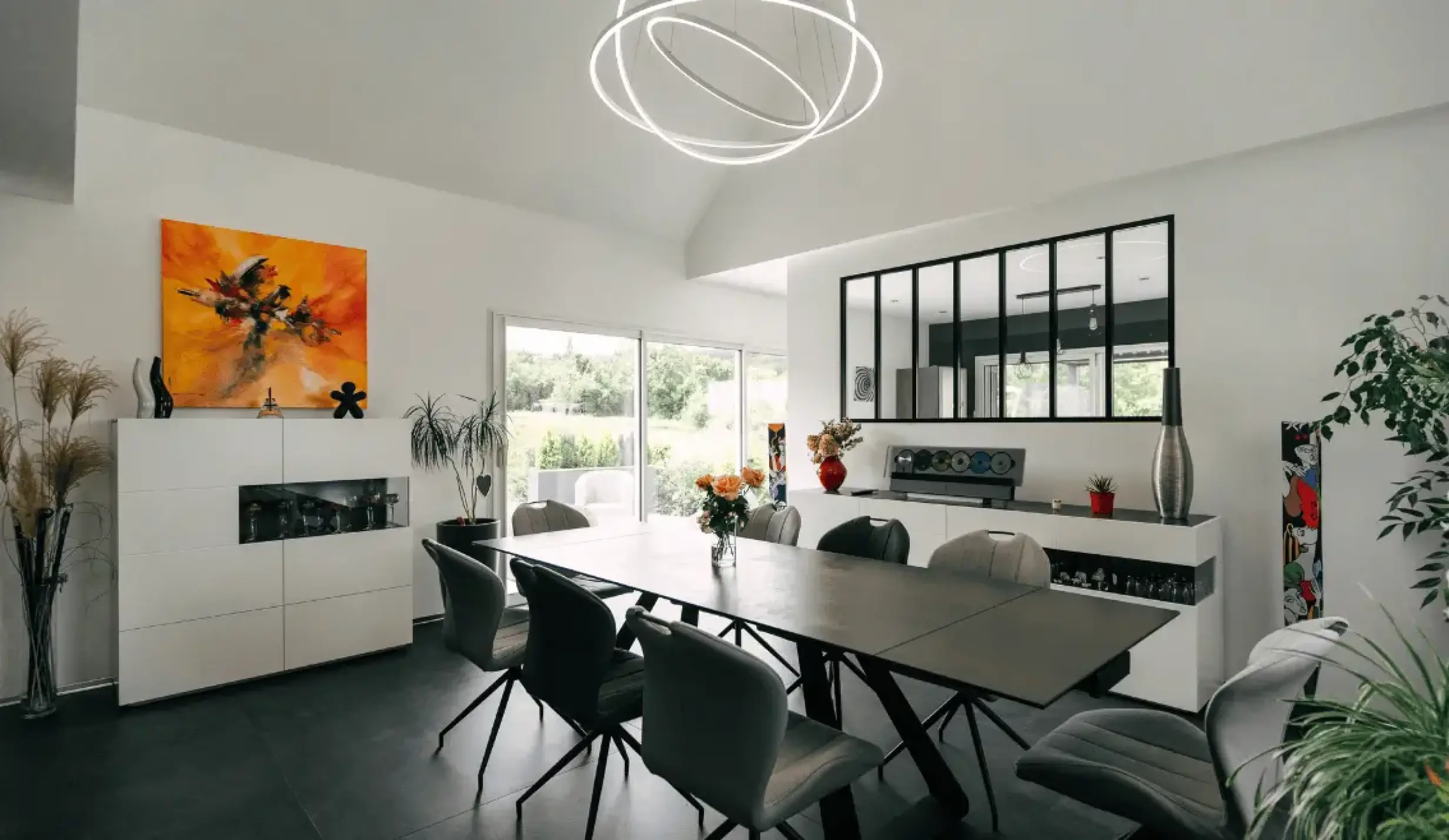 Salle à manger moderne avec verrière et luminaire design dans une maison Stéphane Berger.